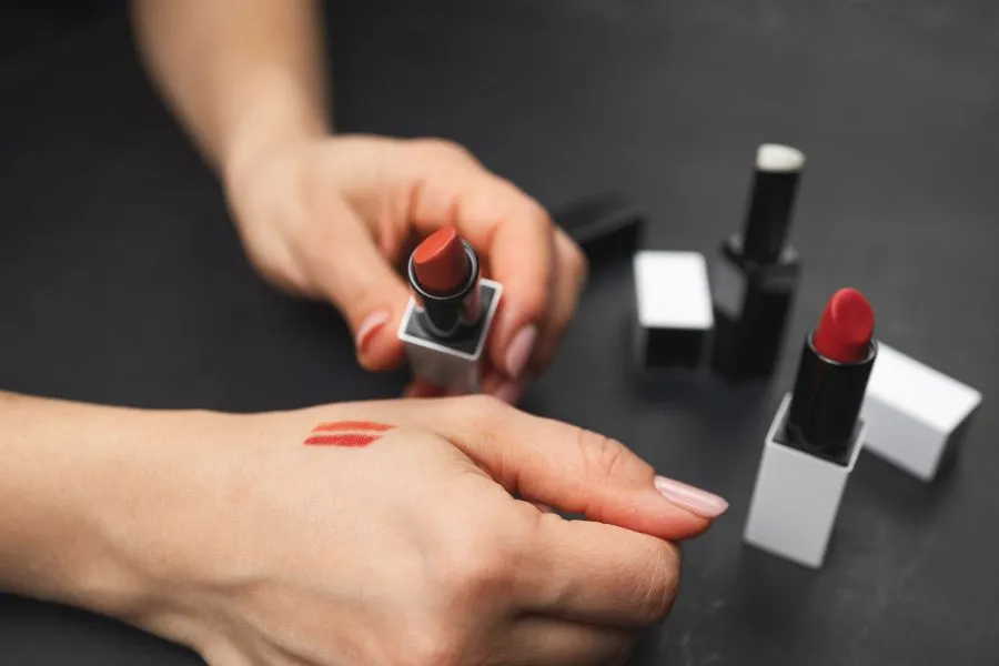 woman testing different lipstick products on her hand